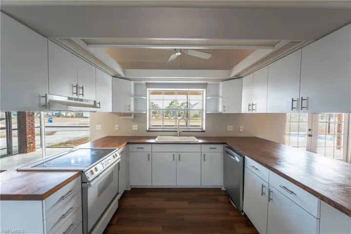 Kitchen featuring white electric range oven, open shelves, white cabinetry, dishwasher, and dark wood-style flooring