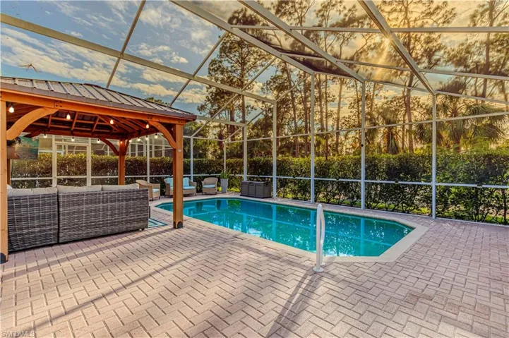 View of swimming pool featuring glass enclosure, a gazebo, outdoor lounge area, and a patio