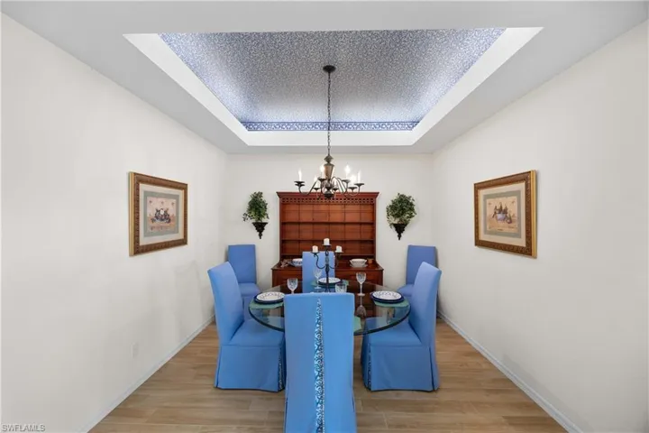 Dining room featuring a tray ceiling, wood finish floors, and a chandelier