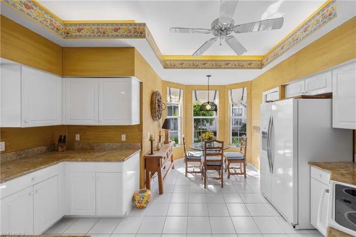 Kitchen with white appliances, white cabinetry, a ceiling fan, hanging light fixtures, and light tile patterned flooring