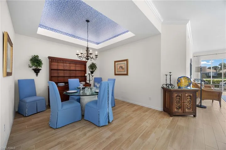 Dining room featuring a raised ceiling, light wood-style floors, and a chandelier