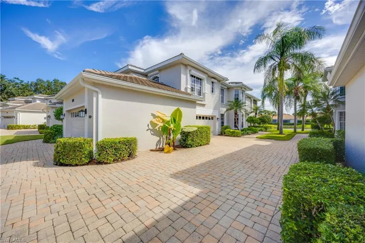View of property exterior with a residential view, decorative driveway, stucco siding, and an attached garage