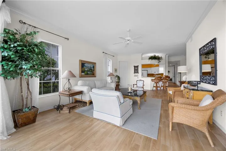 Living room with light wood-style floors, crown molding, and a ceiling fan