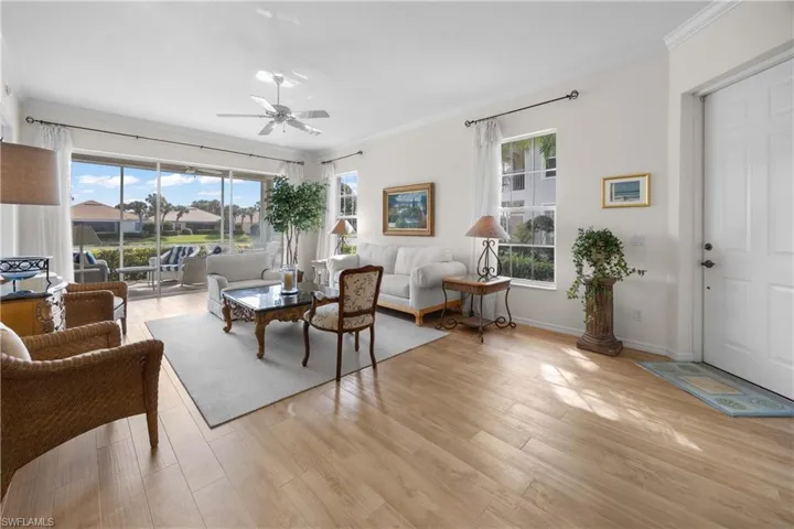 Living area featuring ornamental molding, light wood-type flooring, and ceiling fan