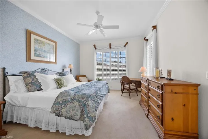 Bedroom featuring crown molding, light carpet, ceiling fan, and wallpapered walls