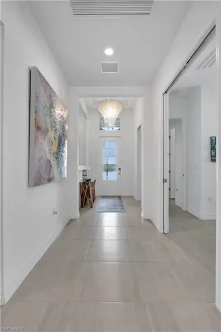 Hallway featuring light Tile Patterned Floors and a notable chandelier