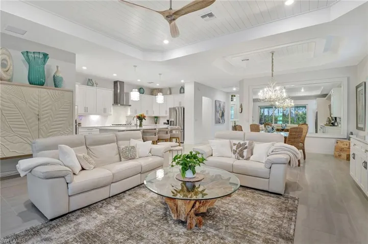Living room featuring wooden Ceiling, Ceiling Fan with Magnificent Chandelier, and Tray Ceiling