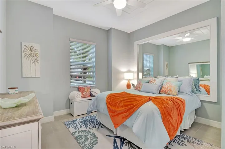 Bedroom with light tile patterned flooring, multiple windows, and ceiling fan
