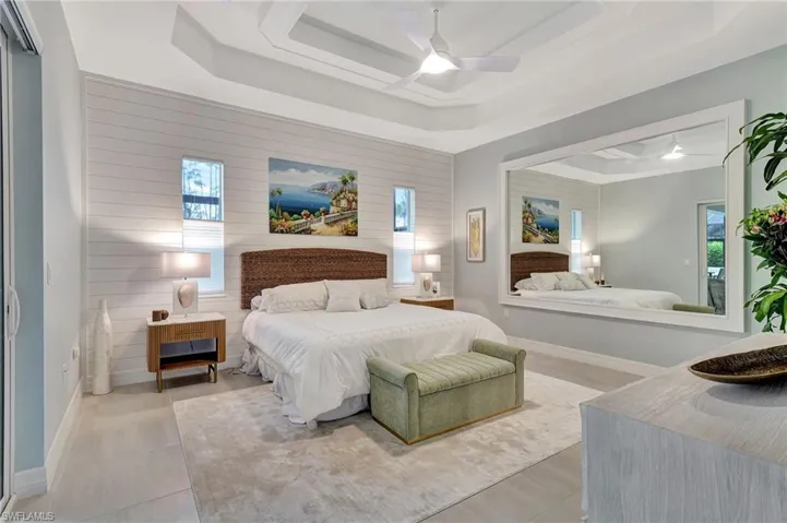 Primary bedroom with Custom Wall and Finished Mirror with Trim and featuring Ship wall and Tray Ceiling