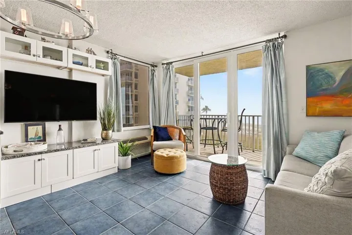 Living area with a textured ceiling, dark tile patterned floors, and suspended lighting