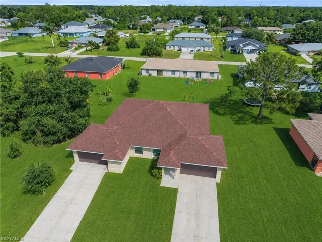 Split-level residential structure featuring a shingled roof, two garage doors, and individual concrete driveways
