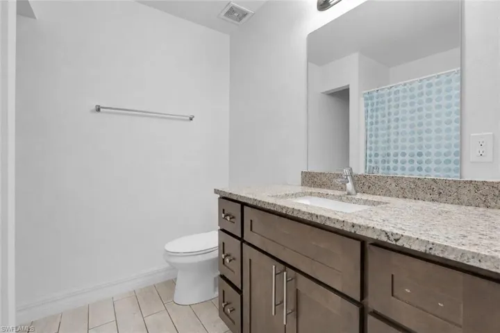 Bathroom vanity with a light-colored granite countertop, undermount sink, and wood-finish cabinetry
