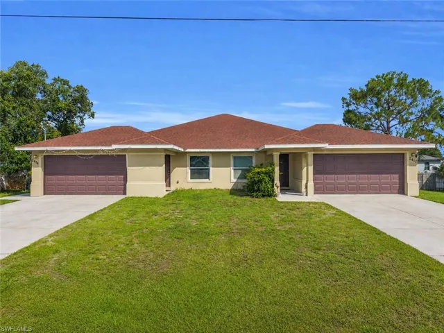 Duplex property featuring a neutral stucco exterior, brown garage doors, a red tile roof, and individual concrete driveways