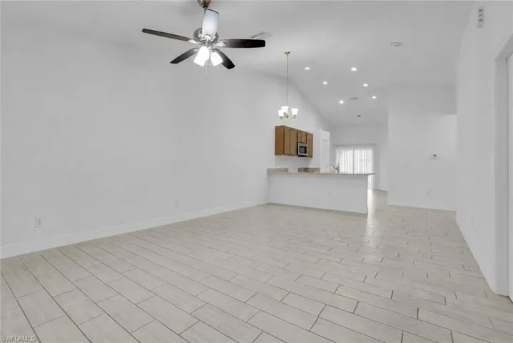 Vaulted ceilings, recessed lighting, and a ceiling fan enhance the main living area