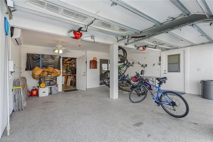Garage with ceiling fan, an AC wall unit, and a garage door opener