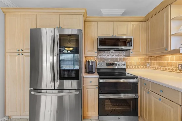 Kitchen with light brown cabinets, tasteful backsplash, and stainless steel appliances
