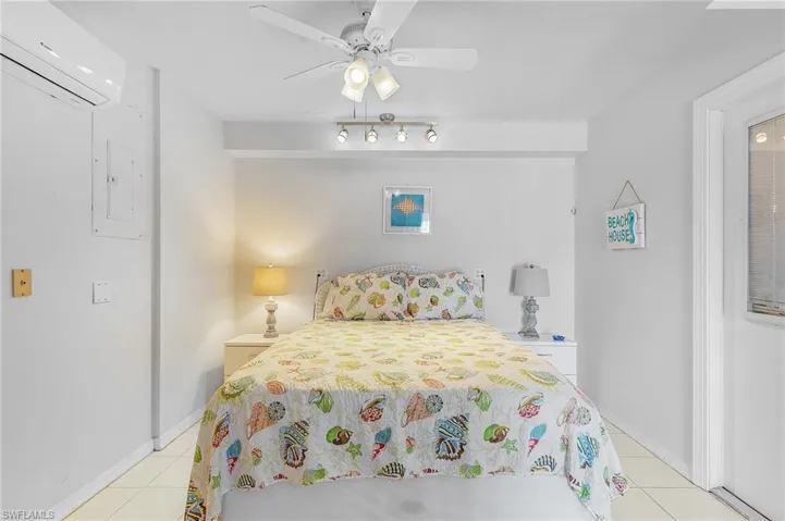 Tiled bedroom featuring a closet, a wall mounted AC, and ceiling fan