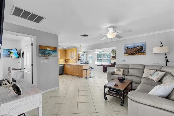 Living room featuring ornamental molding, light tile patterned flooring, and ceiling fan