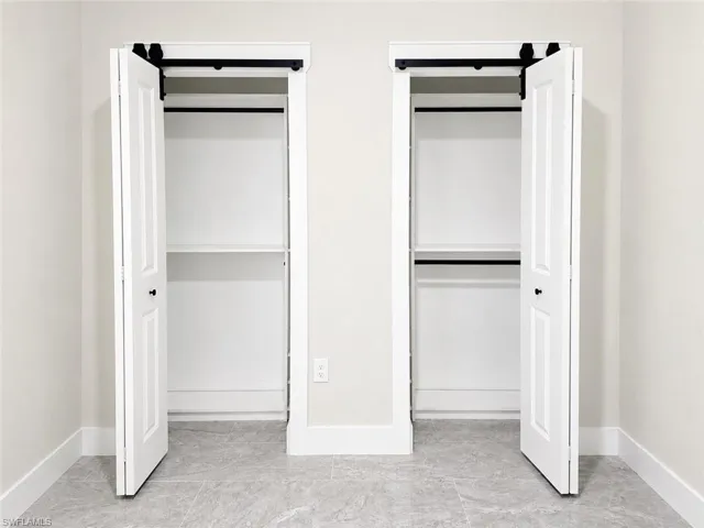 Twin closets featuring white bifold doors with black hardware, interior shelving, and hanging rods