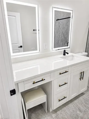 Dual illuminated mirrors above a long vanity with a white countertop and integrated sink