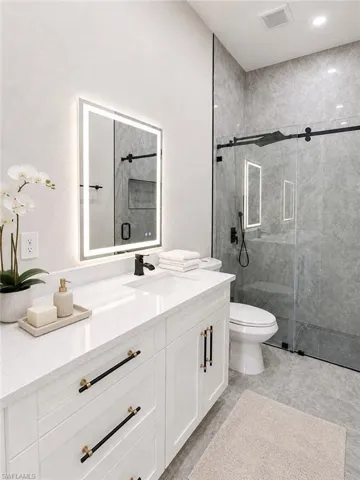 Vanity with white shaker cabinetry, quartz countertop, and black hardware