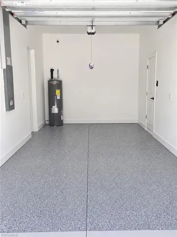 Attached two-car garage featuring a speckled epoxy floor coating, white baseboards, and a water heater unit