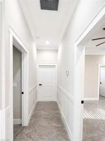 Hallway featuring wainscoting, crown molding, recessed lighting, and gray stone-finish flooring
