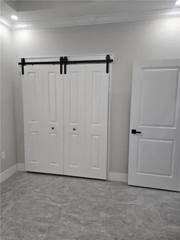 Closet featuring white bi-fold doors with black barndoor hardware
