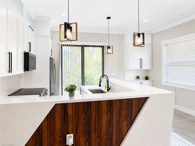 Modern kitchen featuring white cabinetry, light countertops, and a wood-finish accent panel on the island