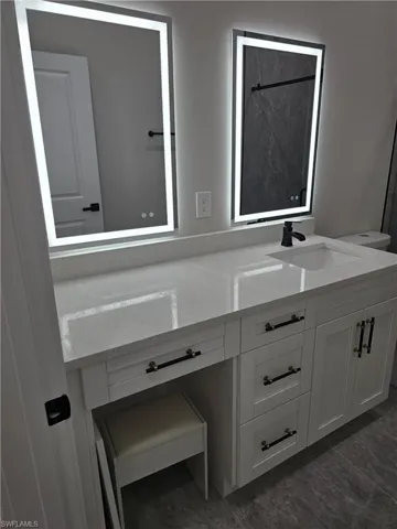 Dual illuminated mirrors over a white vanity with integrated sinks