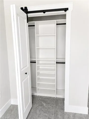 Modern closet system featuring a barn door entry, integrated shelving, and hanging rods