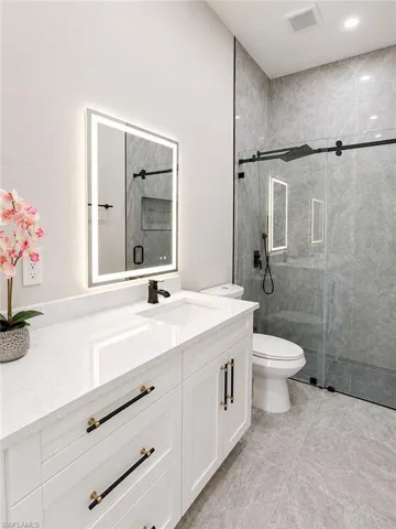 Modern bathroom featuring a white vanity with a quartz countertop, an undermount sink, and a black faucet