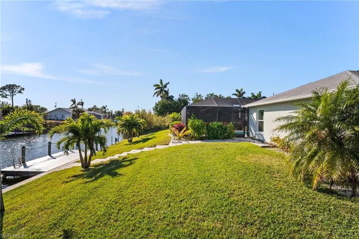 View of yard featuring a water view, a dock, and glass enclosure