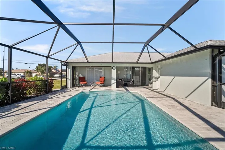 View of pool with a patio area and glass enclosure