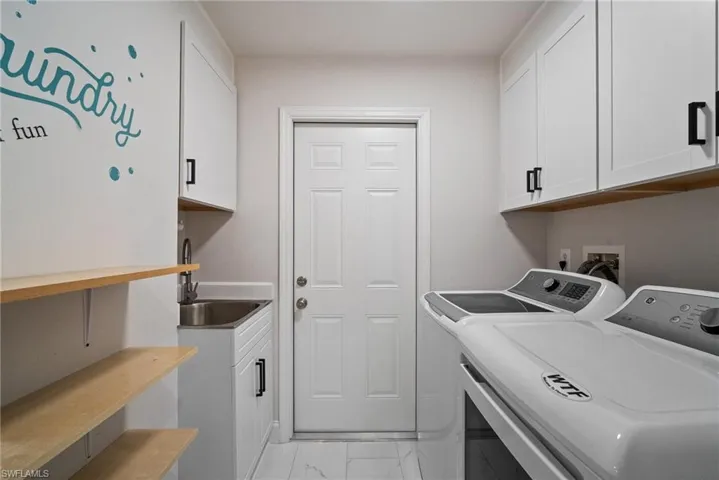 Clothes washing area featuring cabinets, washer and dryer, and sink