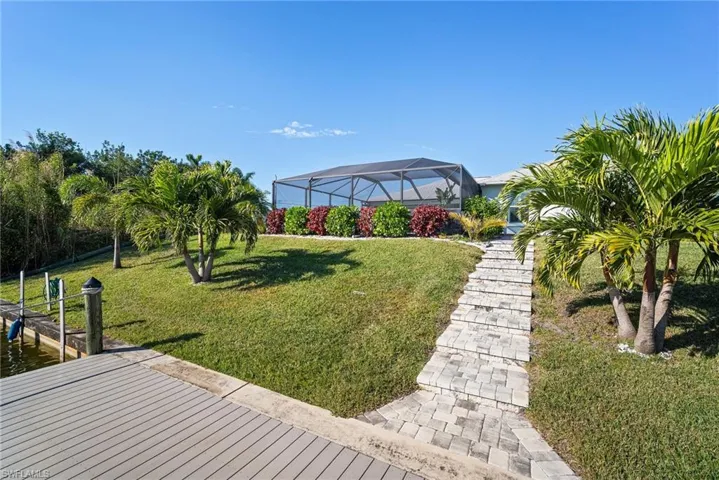 View of yard featuring a water view, glass enclosure, and a boat dock
