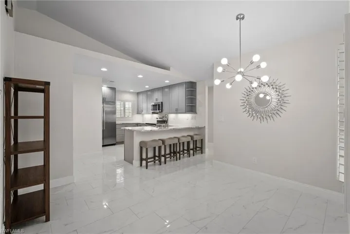 Kitchen featuring lofted ceiling, a kitchen breakfast bar, stainless steel appliances, kitchen peninsula, and a chandelier