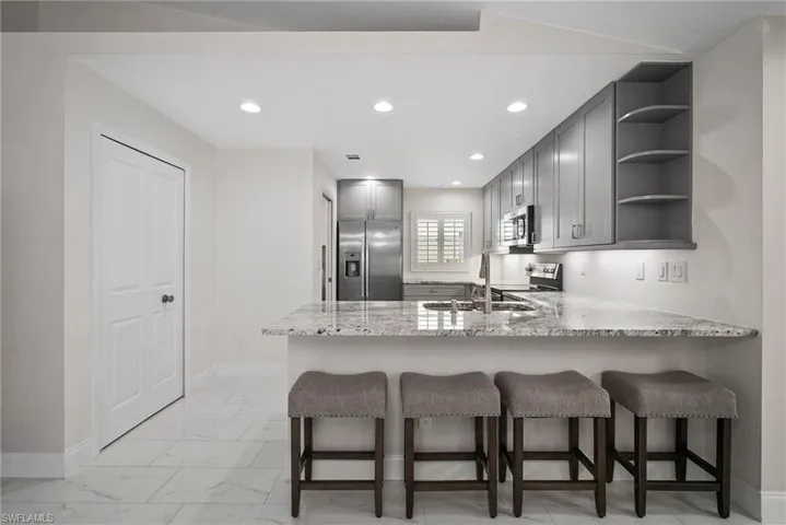 Kitchen featuring gray cabinets, sink, kitchen peninsula, stainless steel appliances, and light stone countertops