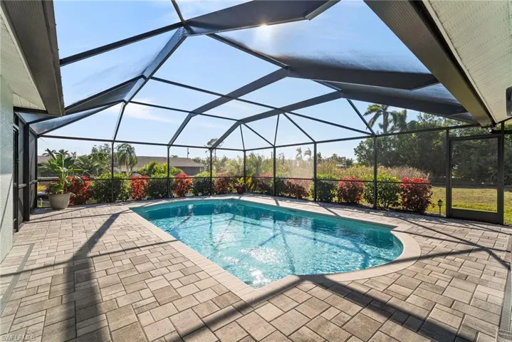 View of swimming pool with glass enclosure and a patio area