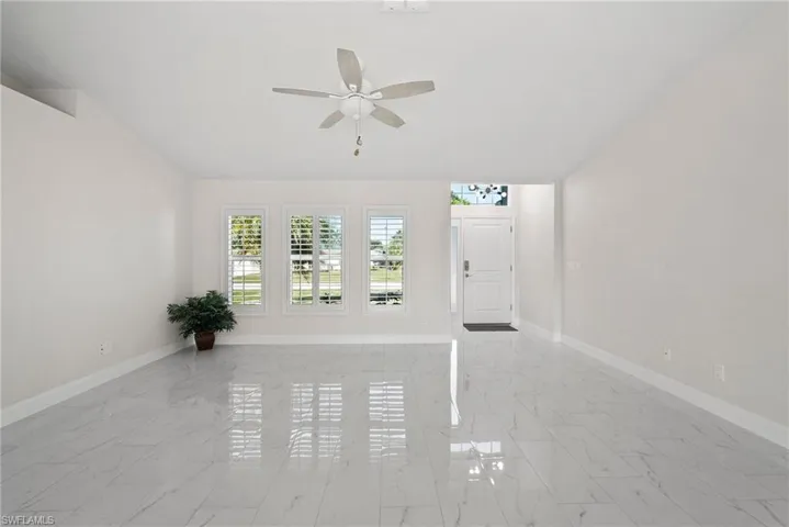 Unfurnished living room featuring ceiling fan and vaulted ceiling