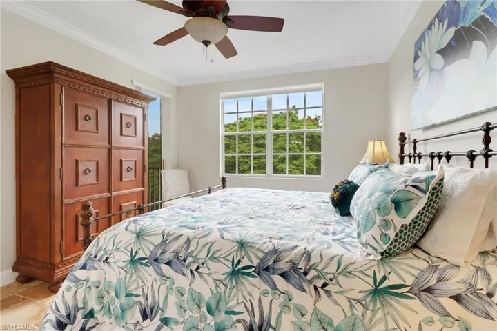 Bedroom with ornamental molding, ceiling fan, and light stone finish flooring