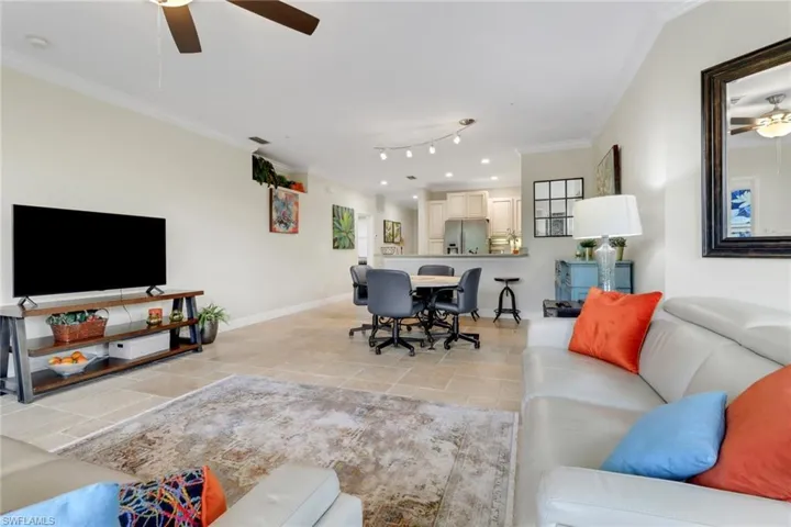Living room with ceiling fan, ornamental molding, recessed lighting, and light stone finish flooring