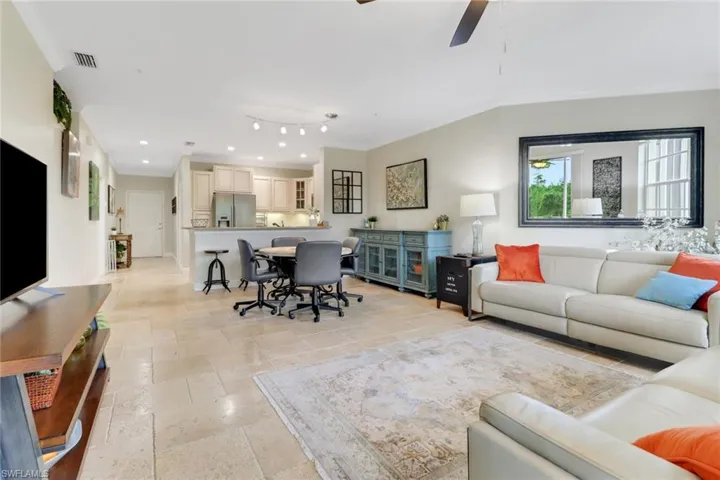Living room featuring ornamental molding, recessed lighting, stone tile flooring, and ceiling fan