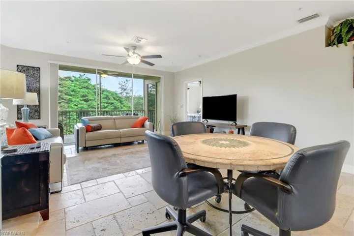 Dining room featuring stone tile flooring, ornamental molding, and ceiling fan