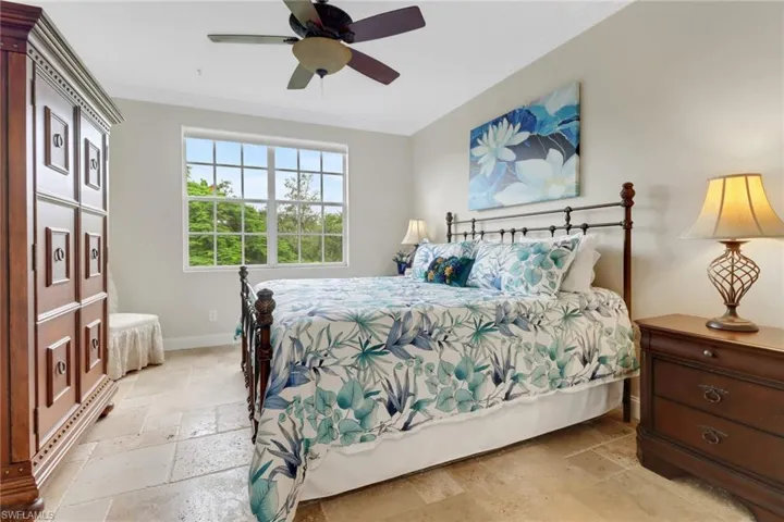 Bedroom with stone tile flooring, crown molding, and a ceiling fan