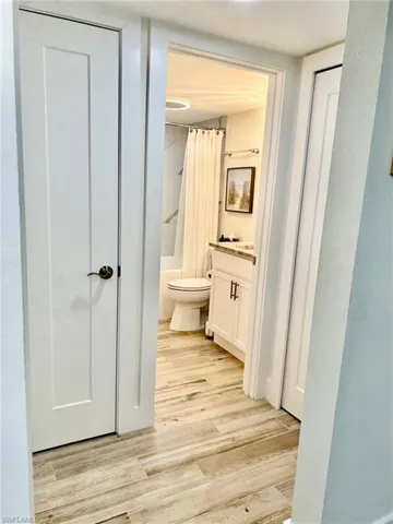 Full bathroom with wood-type flooring, toilet, vanity, and shower / tub combo with curtain
