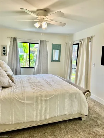 Bedroom featuring multiple windows, carpet floors, and ceiling fan