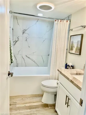 Full bathroom featuring shower / tub combo, hardwood / wood-style floors, toilet, and vanity