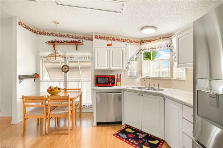 Kitchen featuring a sink, light countertops, light wood-type flooring, appliances with stainless steel finishes, and white cabinetry