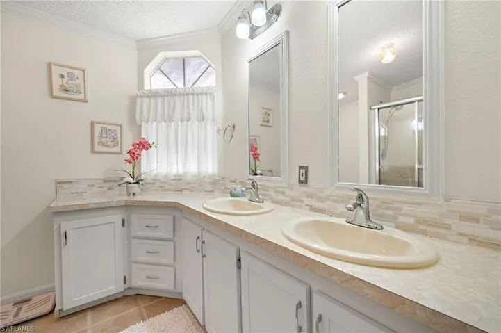 Bathroom featuring a sink, backsplash, a stall shower, and crown molding